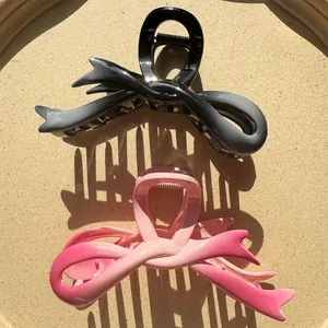 Gradient ribbon style hair claw clips in black grey and pink shown on beige tray
