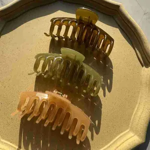 Three translucent jelly-colored hair claws in amber, green, and pink on a matte tray