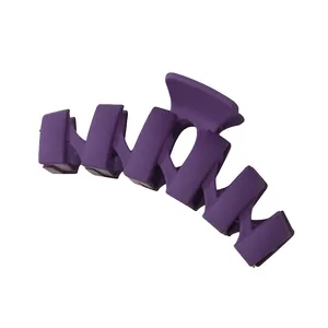 Macro detail of purple matte wavy claw clip showing elegant geometric curves and finish