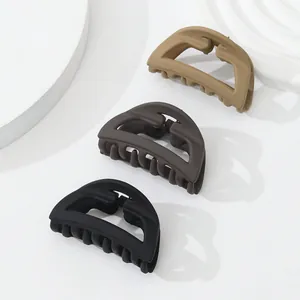 Close-up of three matte hair claws in neutral black, coffee, and khaki earth tones