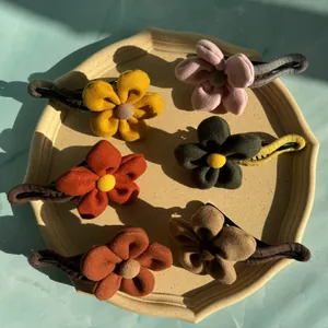 Set aus 6 Plüsch-Blumen-Haarspangen in Vintage-Farben auf einem Keramiktablett präsentiert