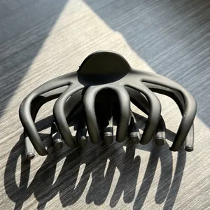 Macro detail of matte black octopus hair claw clip with multi-teeth grip on wood surface