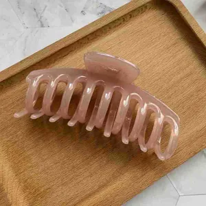 Detail of large pastel pink hair claw clip with dragon bone design on marble surface