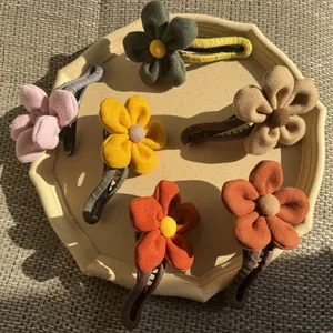 Set mit fünf Plüsch-Blumen-Haarspangen in verschiedenen Farben auf einem Keramiktablett