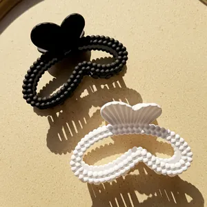 Mollette per capelli opache a forma di cuore, nero e bianco con design a perline su fondo