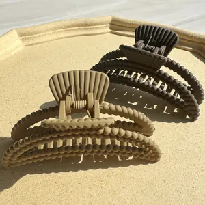 Matte coffee and beige beaded moon hair claws displayed on a textured tray