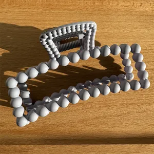 Macro detail of a grey matte rectangular claw clip with a stylish beaded frame design