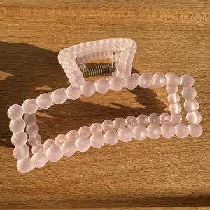 Close-up of a matte pink square hair claw clip with bubble design on wood surface