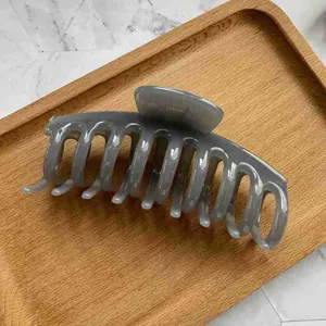 Macro view of a smoky grey translucent hair claw clip on a stylish wooden tray