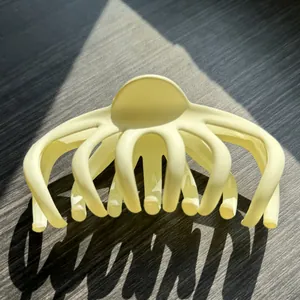 Macro shot of matte cream octopus hair claw clip on dark wood with dramatic shadows