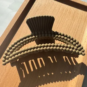 Macro detail of khaki hair claw clip with bubble texture and matte finish on wood