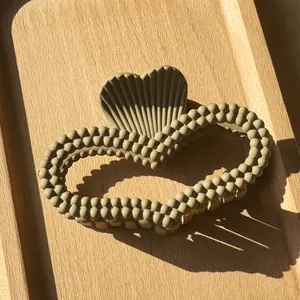 Detail of matte heart claw clip with bead texture and striped accent on wooden tray