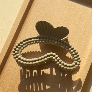 Dettaglio ravvicinato di una pinza per capelli beige opaco con trama a perle fini