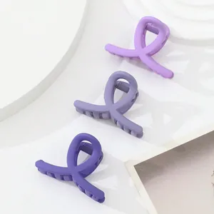 Detailed view of three matte purple gradient mini hair claws on a minimalist stone display