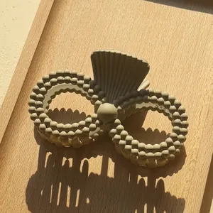 Close-up of matte taupe hair claw clip with double-ring structure and bead texture on wood