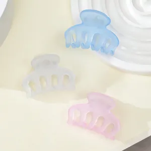 Detailed view of three mini matte hair claws in pastel blue, white, and soft pink colors