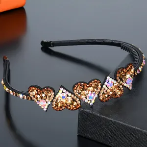 Makroansicht des Herz-Haarreifens mit bunten Strasssteinen auf schwarzem Stirnband