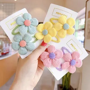 Close-up of cute knitted flower hair ties in pink, yellow and blue on a display card