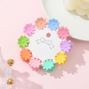 Close-up of ten colorful mini daisy hair clips arranged on a white card display