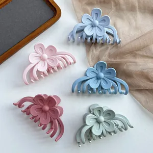 Pinces à cheveux fleurs mates en cinq couleurs pastel sur un plateau en bois décoratif