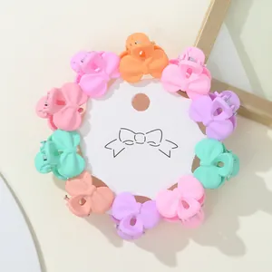 Macro detail of colorful bow-shaped mini hair claws on white round card packaging