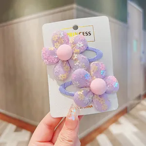 Close-up of a pair of purple mesh flower hair clips with sequins on a branded white card