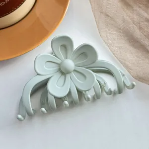 Détail de la pince à cheveux fleur verte mate avec design lisse à cinq pétales sur fond blanc