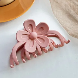 Détail d'une pince à cheveux fleur rose mat posée sur une assiette orange et filet