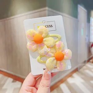 Close-up of yellow floral BB hair clips for girls featuring pink flower print details