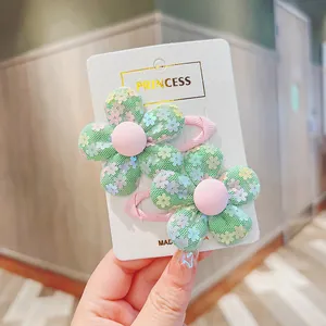 Detail of green mesh flower hair clips with colorful sequins and pink ribbon lining