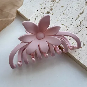 Detail der rosa matten Blumen-Haarklammer mit glatter Textur auf Stein-Hintergrund