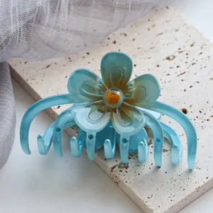 Detail der lichtdurchlässigen blauen Blumen-Haarklammer mit orangefarbenem Farbverlauf