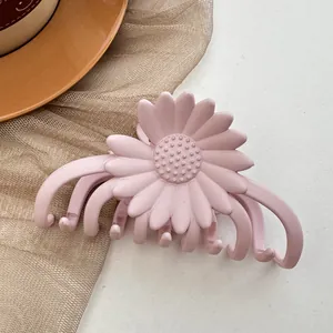Detail of a matte pink daisy flower hair claw clip on a soft textured background