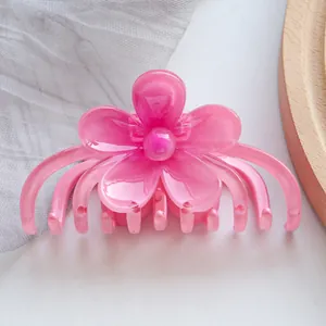 Detail of a glossy pink flower hair claw clip on a rustic wooden plate decoration