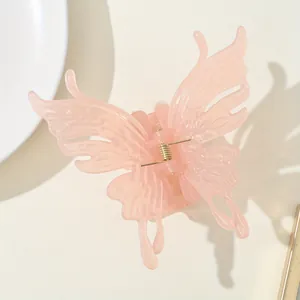 Detailed macro view of a translucent pink butterfly hair claw with golden spring mechanism