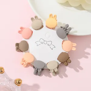 Close-up of ten mini rabbit ear hair claws in pastel macaron colors on a round card