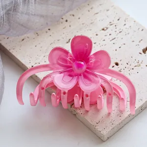 Nahaufnahme einer rosa Blumen-Haarklammer auf einem strukturierten Steinuntersetzer