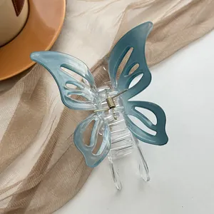 Macro view of butterfly hair claw clip with blue gradient wings on a beige gauze background