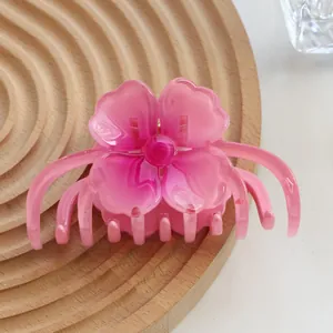 Close-up of a pink gradient floral hair claw clip on a wooden display stand