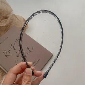 Détail du serre-tête ondulé en métal noir avec design en spirale et embouts protecteurs