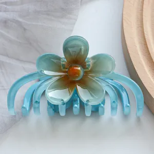 Detailed macro of translucent blue flower hair claw clip with amber center on fabric