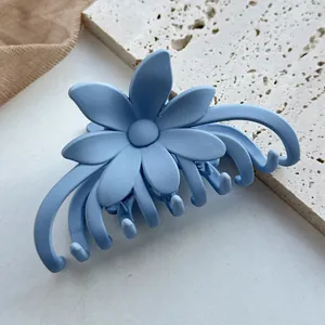 Nahaufnahme einer mattgrauen blauen Blumen-Haarklammer auf einem minimalistischen Stein