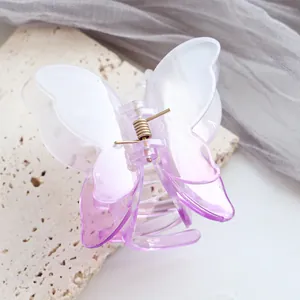 Dettaglio di molletta per capelli a farfalla sfumata viola con molla dorata su pietra