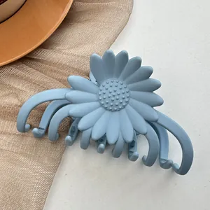 Detail view of a light blue matte daisy hair claw clip with a spring and gripping teeth