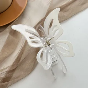 Detail view of cream butterfly hair claw clip with hollow wings and metal spring