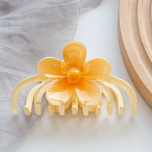 Close-up of a yellow flower-shaped hair claw clip with glossy petals and sturdy teeth