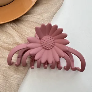 Detailed close-up of a matte pink daisy hair claw clip with floral resin texture