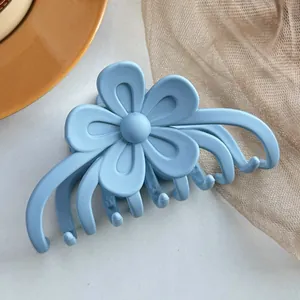 Gros plan d'une pince à cheveux fleur bleu clair mate avec des pétales en résine lisse