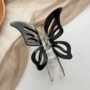 Detail view of hollow butterfly hair claw with black acrylic wings and gold metal spring
