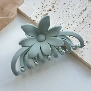 Detail einer matt hellgrünen Blumen-Haarklammer auf weißem Stein und Netzstoff